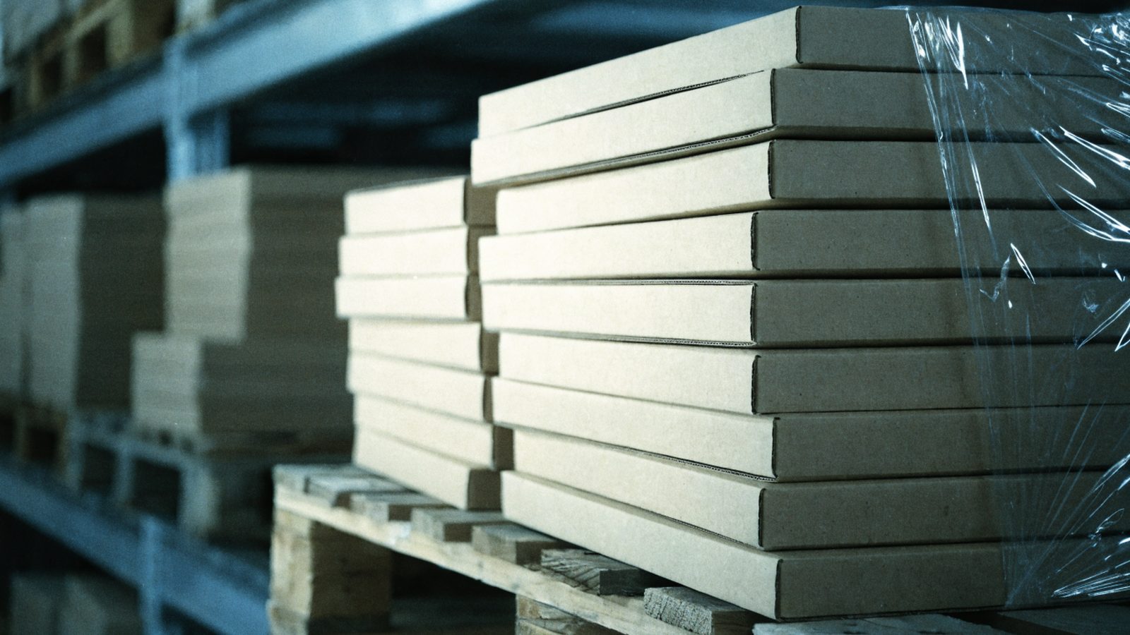 Flat cardboard boxes stacked in even lots on a pallet in a fulfilment warehouse