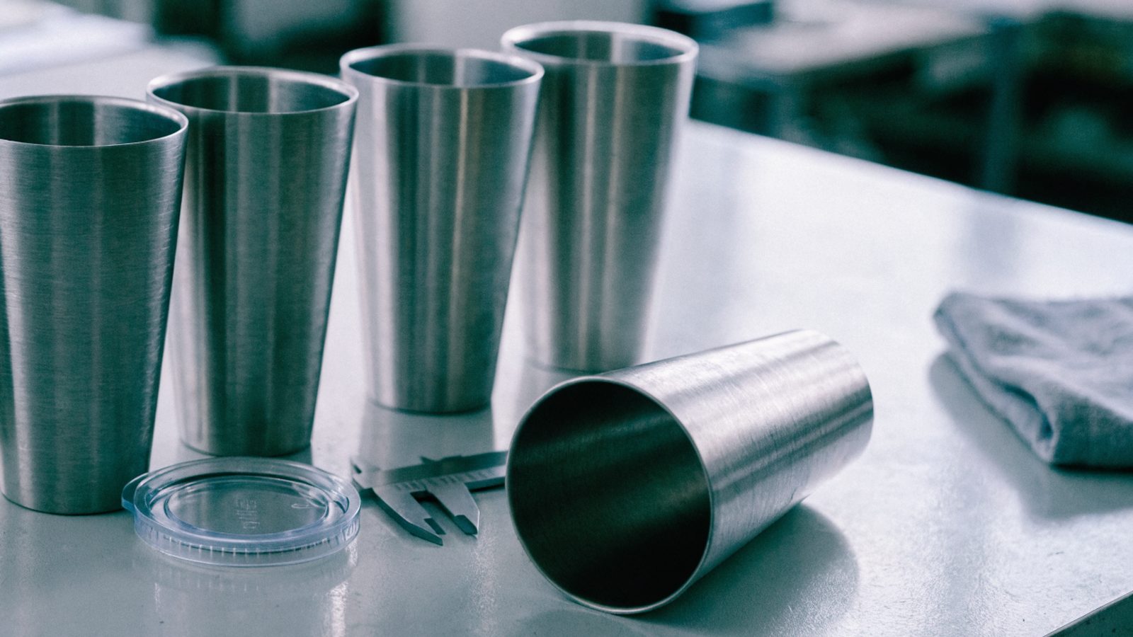 Stainless steel tumblers and calipers on a quality-control bench